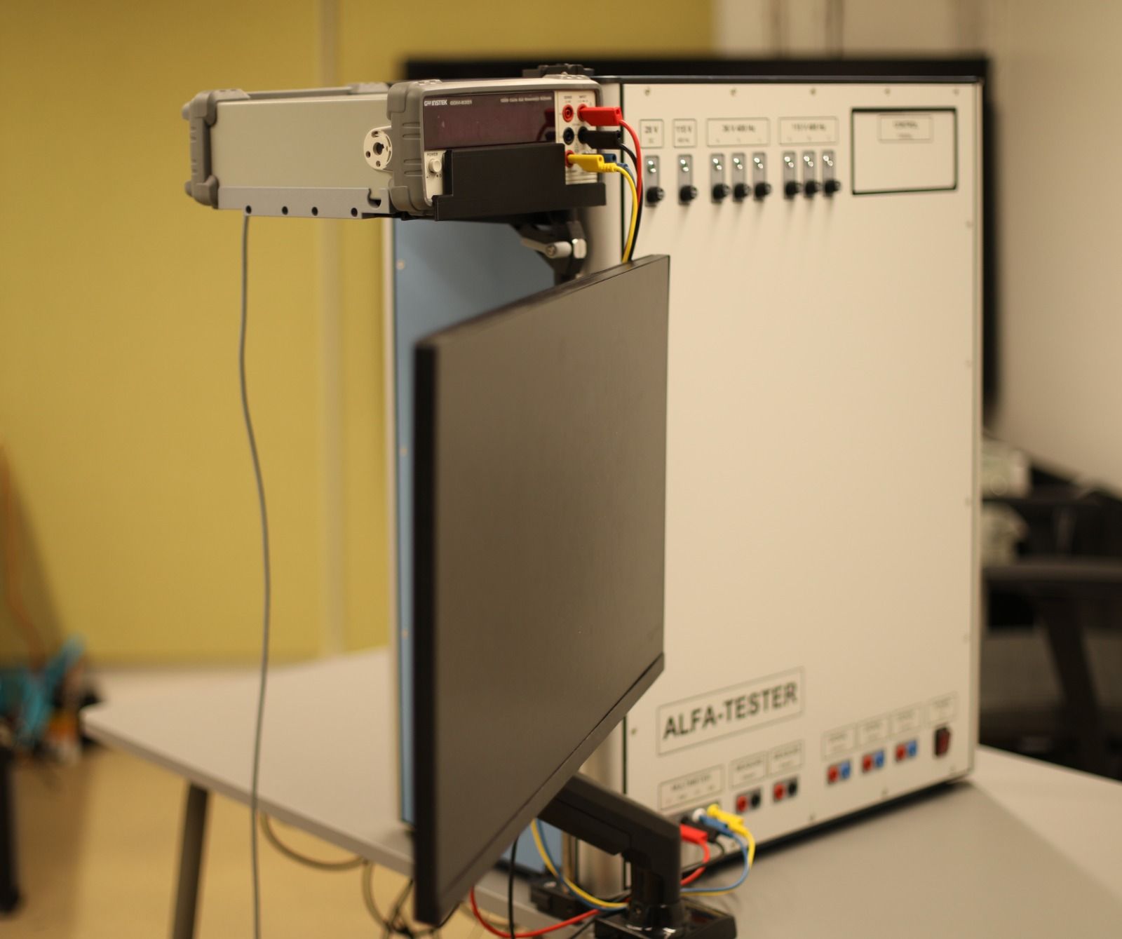 ALFA-TESTER seen from the side, with the GW Instek meter on its swivel platform and the monitor arm